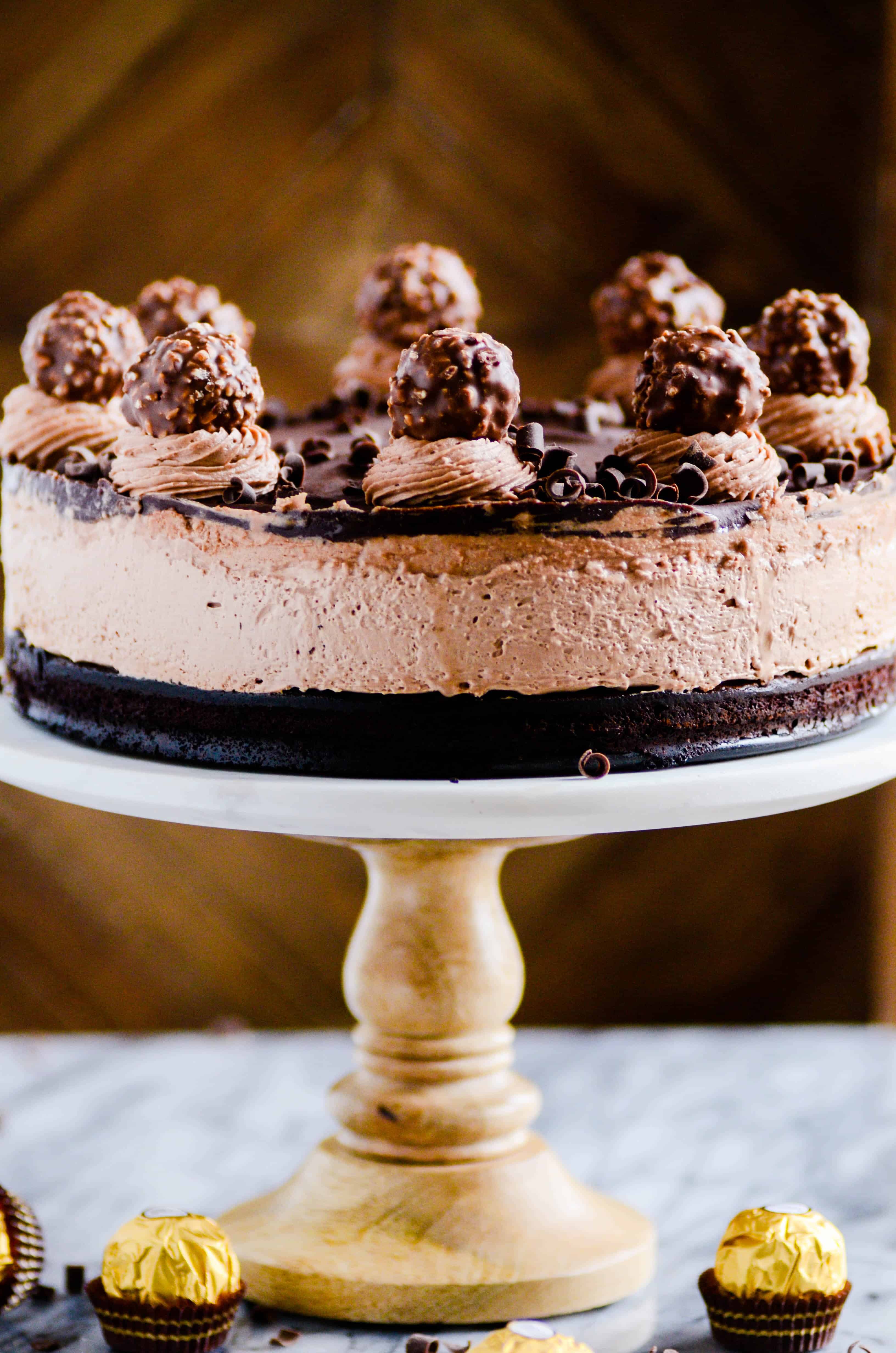 This Nutella Mousse Cake is unreal! Layers of flourless chocolate cake, Nutella mousse, Nutella buttercream, chocolate ganache, and a Ferrero Rocher "cherry" on top.