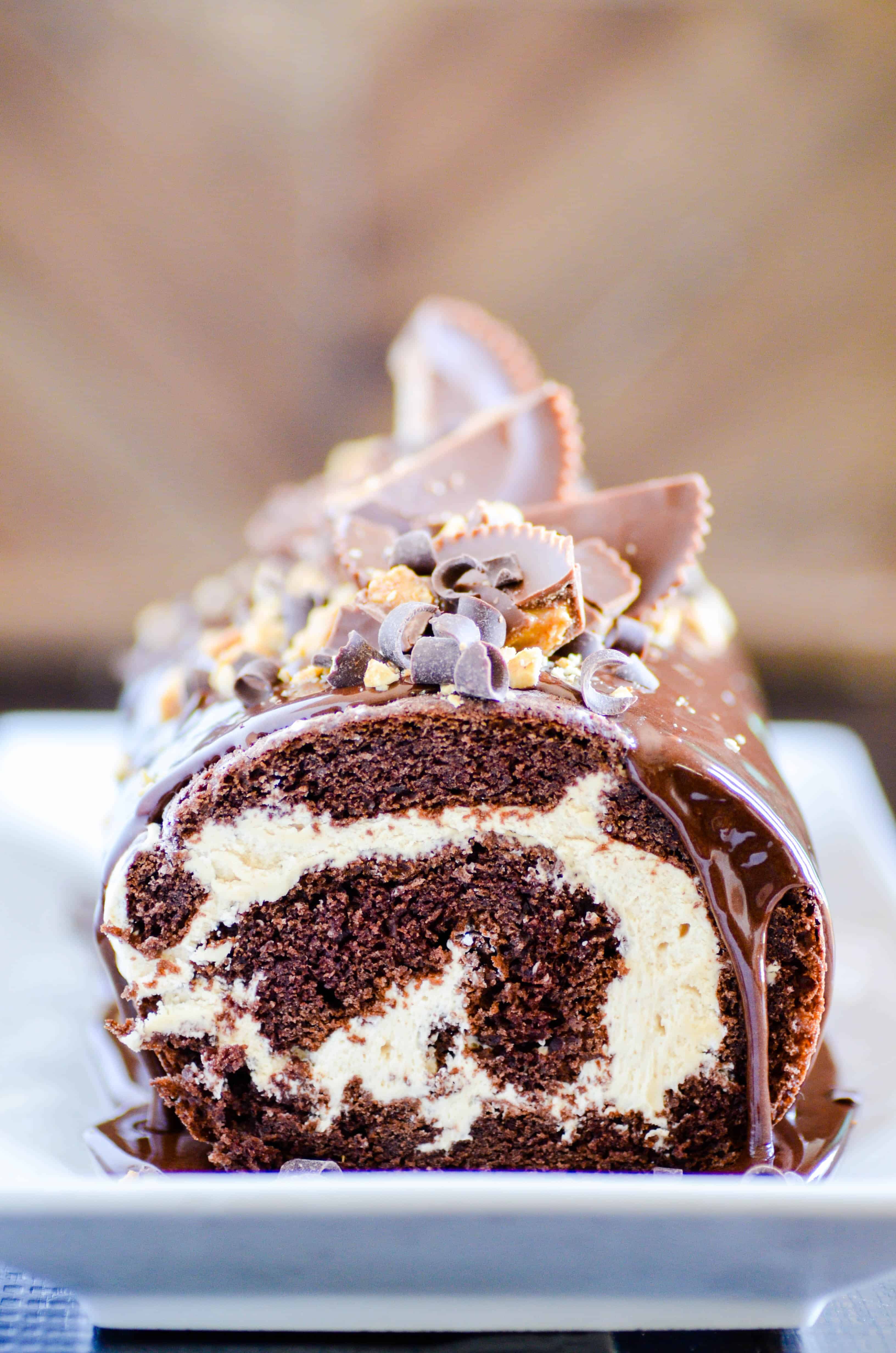 A chocolate cake roll filled with a whipped peanut butter filling topped with chocolate ganache and peanut butter cups.