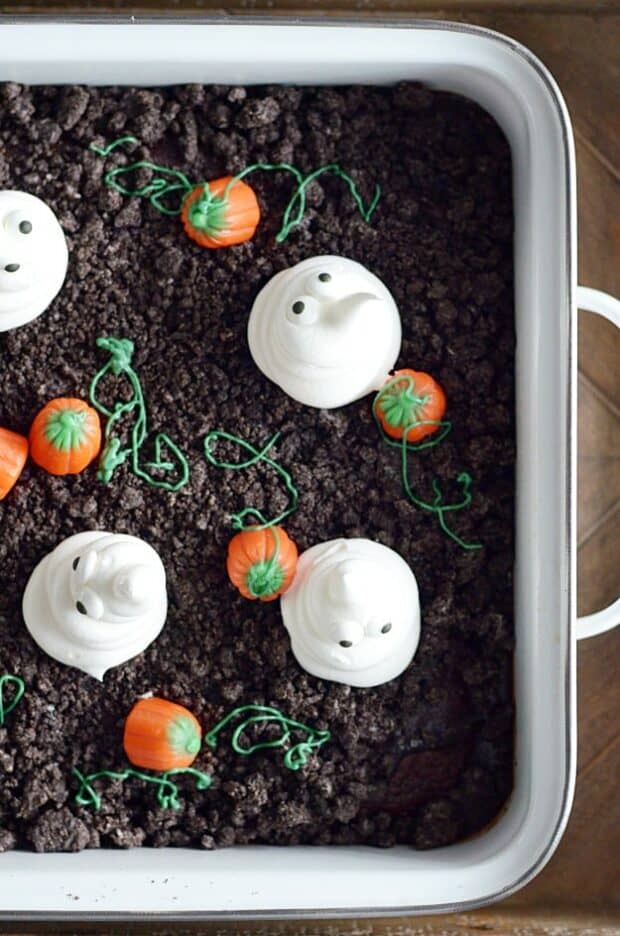 Spooky and cute Halloween cake made with Oreo crumbs, Cool Whip ghosts, and candy corn pumpkins!