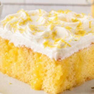 This Lemon Curd Poke Cake is moist, dreamy, and bursting with tart lemon flavor. So easy and absolutely delicious — you have to make this! 🍋